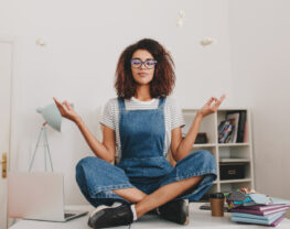 Relaxed young woman sitting in lotus pose on the table