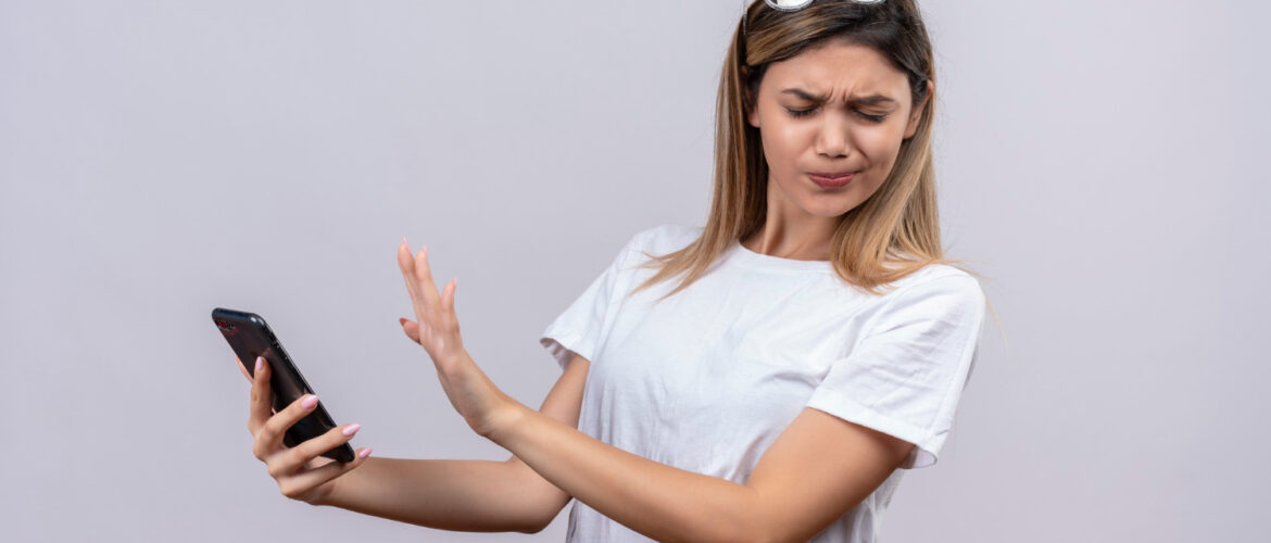 Young woman expressing negativity while holding mobile phone