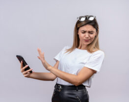 Young woman expressing negativity while holding mobile phone