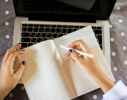 Woman's hands start to write on an empty notepad