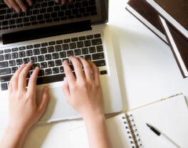 The woman's hands are typing on the laptop.