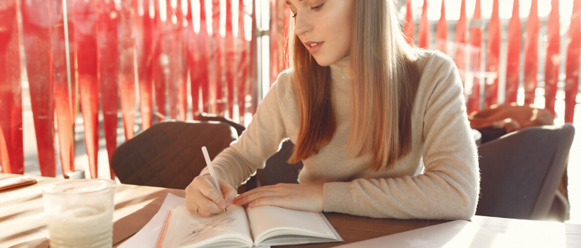 A young woman is writing in the notepad.
