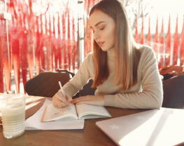 A young woman is writing in the notepad.